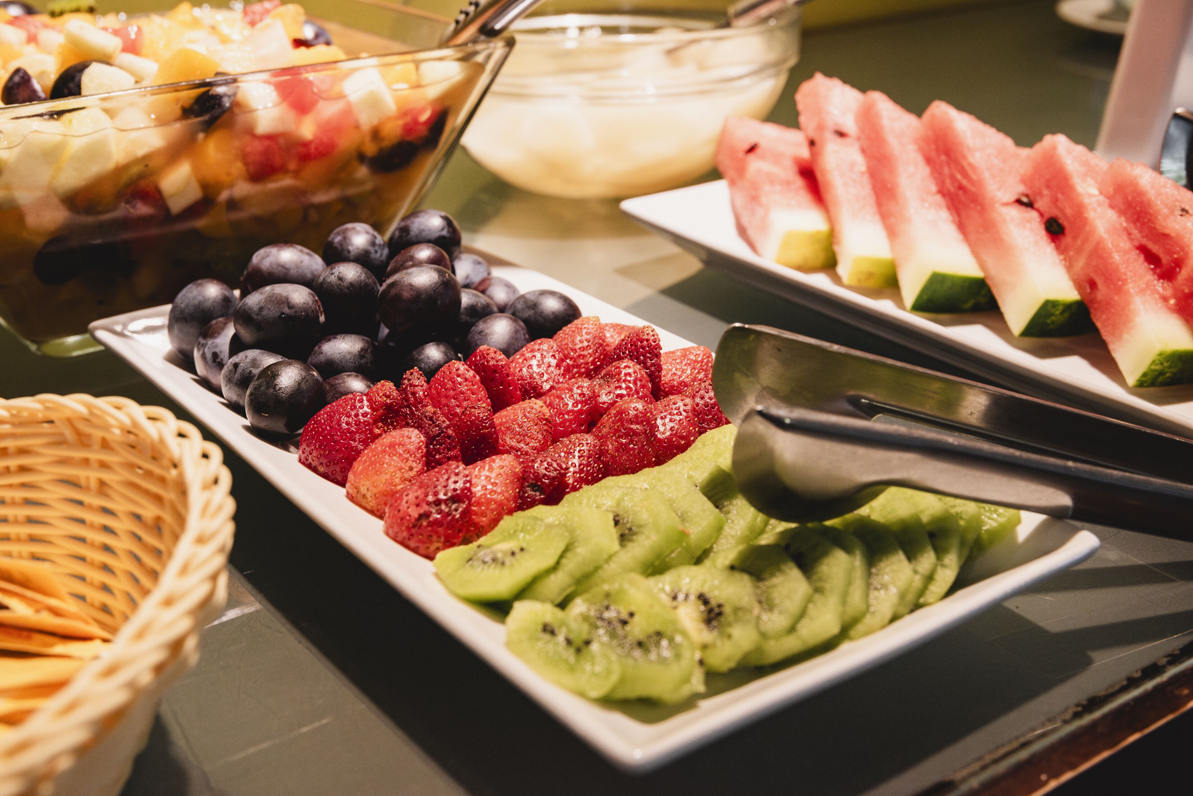 Una mesa de buffet con diversas frutas, como fresas, arándanos, kiwi y sandía.