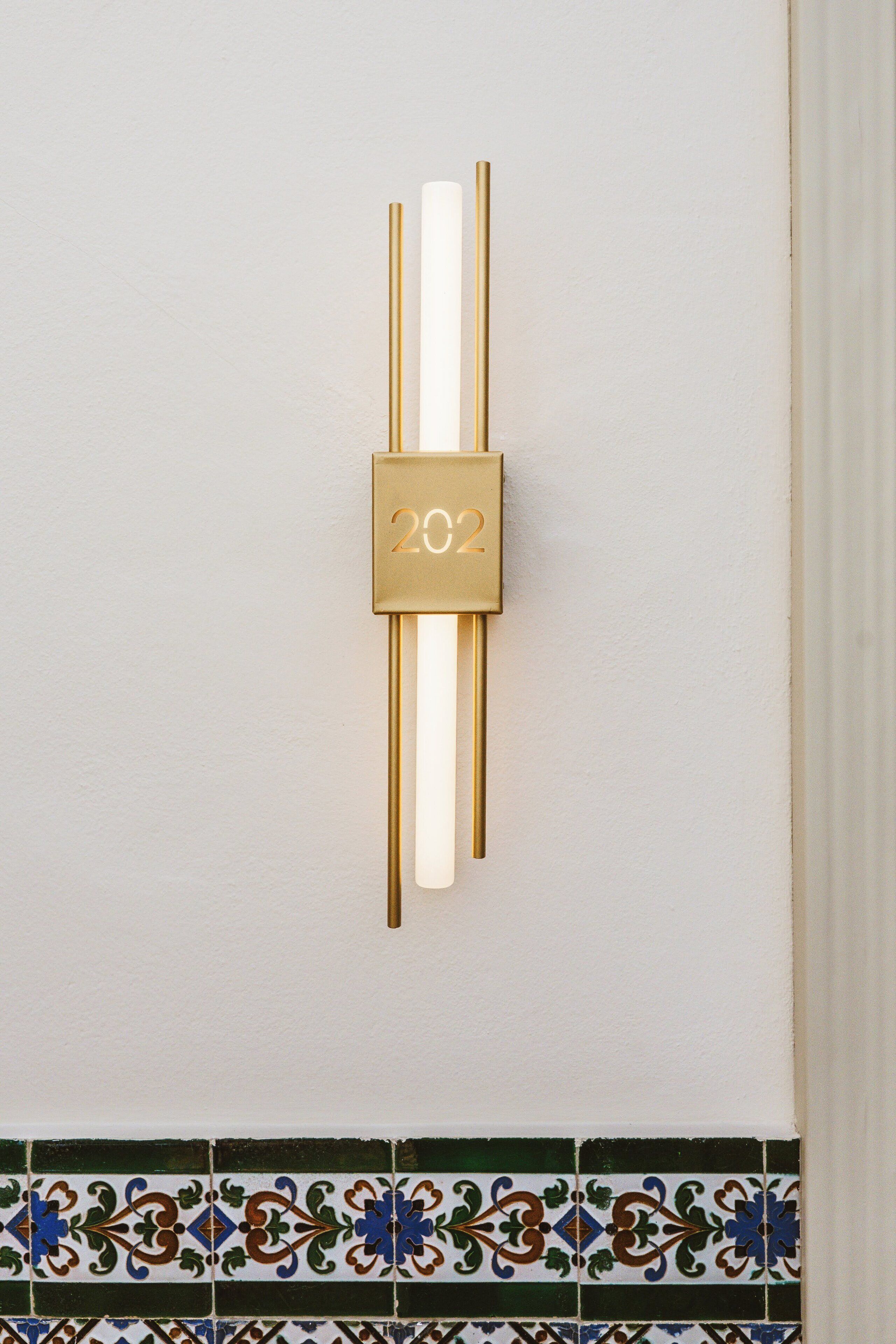 A wall-mounted clock with a minimalist design, featuring two vertical gold bars and a central square with the year '2022' in gold.