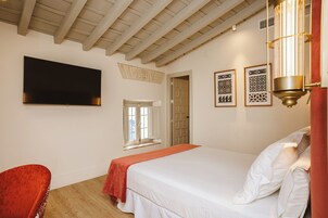 Ein Schlafzimmer mit einem Bett, einem flachbildfernseher an der Wand, einem Fenster und einer Tür.