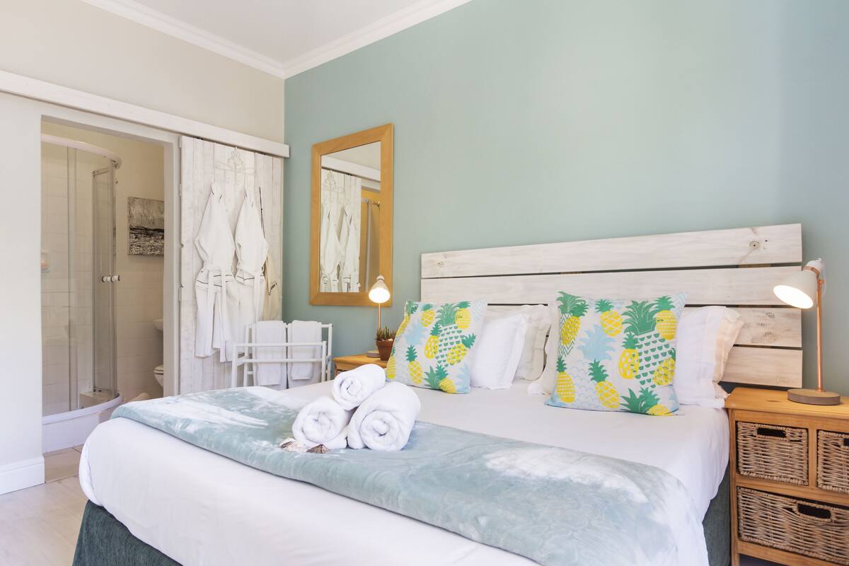 A bedroom with a bed, a wooden headboard, a mirror, and a nightstand with a lamp.