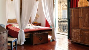 Une chambre à coucher avec un lit en bois, une table de chevet, une valise et une armoire en bois.