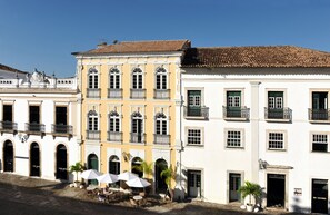 A historic building with multiple balconies, large windows, and a courtyard with outdoor seating.