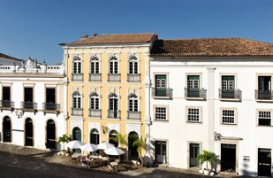 A historic building with multiple balconies, large windows, and a courtyard with outdoor seating.