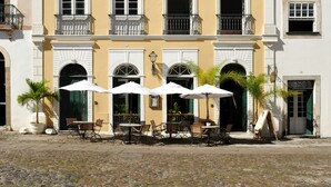 Un immeuble doté de nombreux balcons, d’un sol pavé et d’un espace extérieur aménagé avec des parasols.