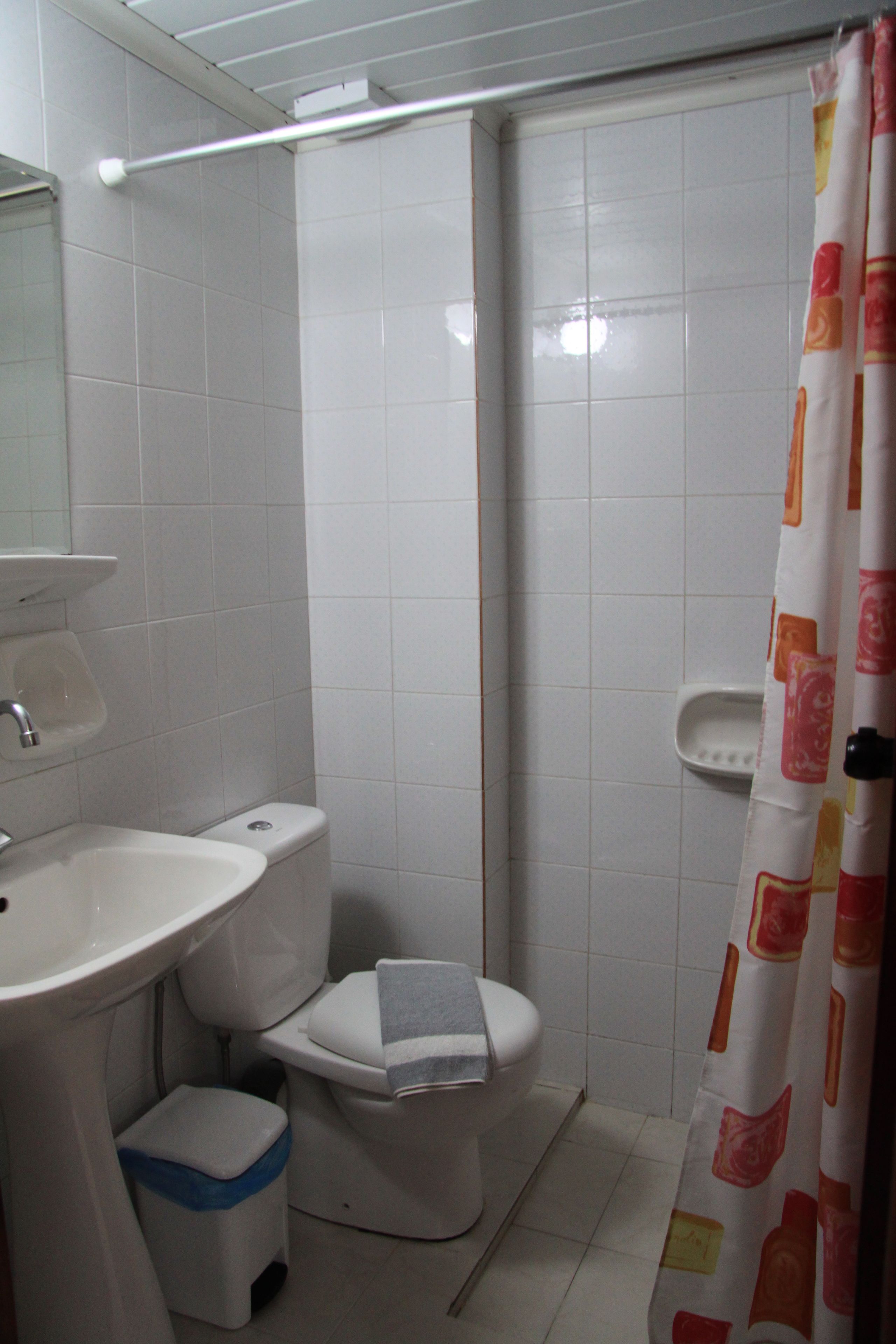 Un baño con lavamanos, inodoro y cortina de ducha.