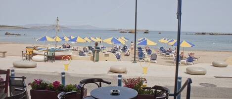 A beachside café with outdoor seating, umbrellas, and a view of the sea.