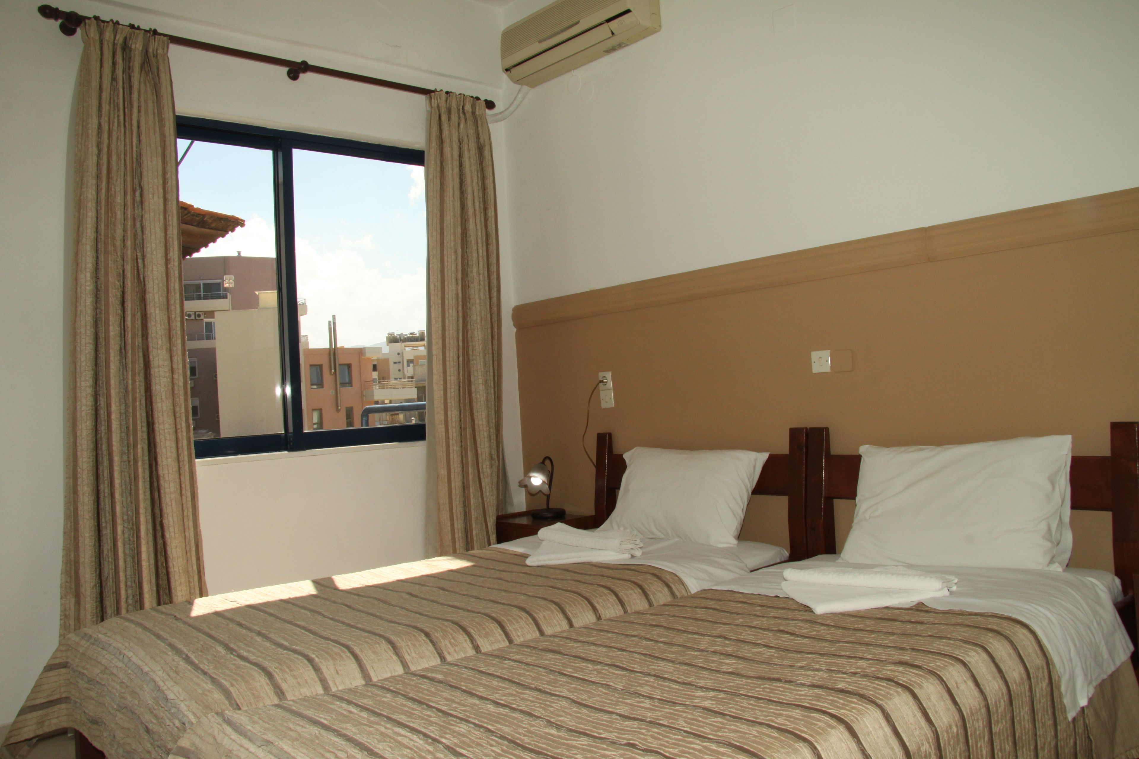 A hotel room with a large bed, a nightstand with a lamp, and a window with curtains.