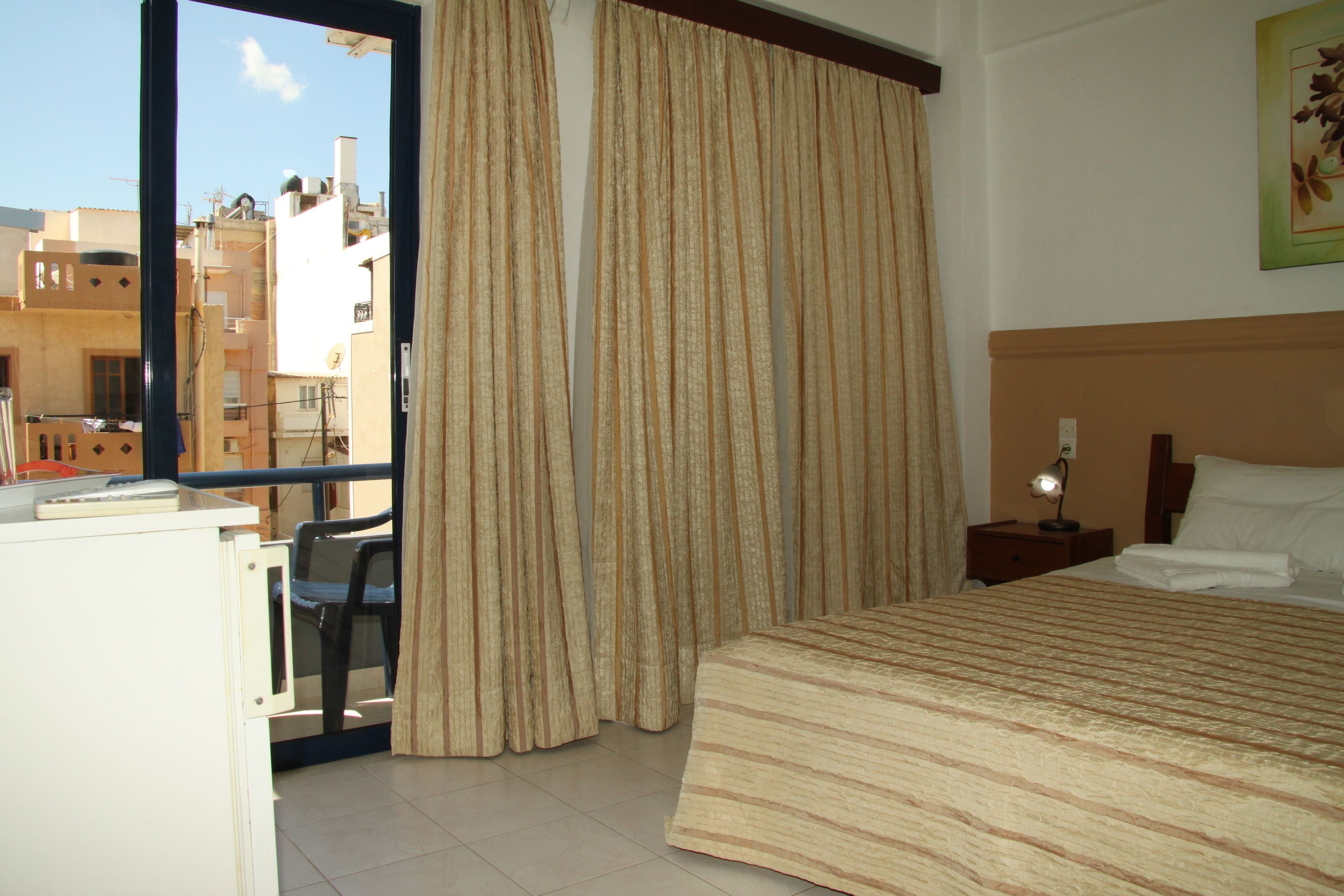 A hotel room with a bed, a desk, a chair, and a window with curtains.