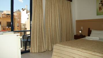 A hotel room with a bed, a desk, a chair, and a window with curtains.