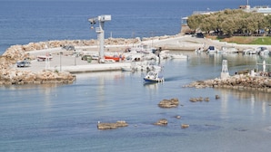 A marina with boats docked, a lighthouse, and a rocky shoreline. - Hotel Danaos (Chania)