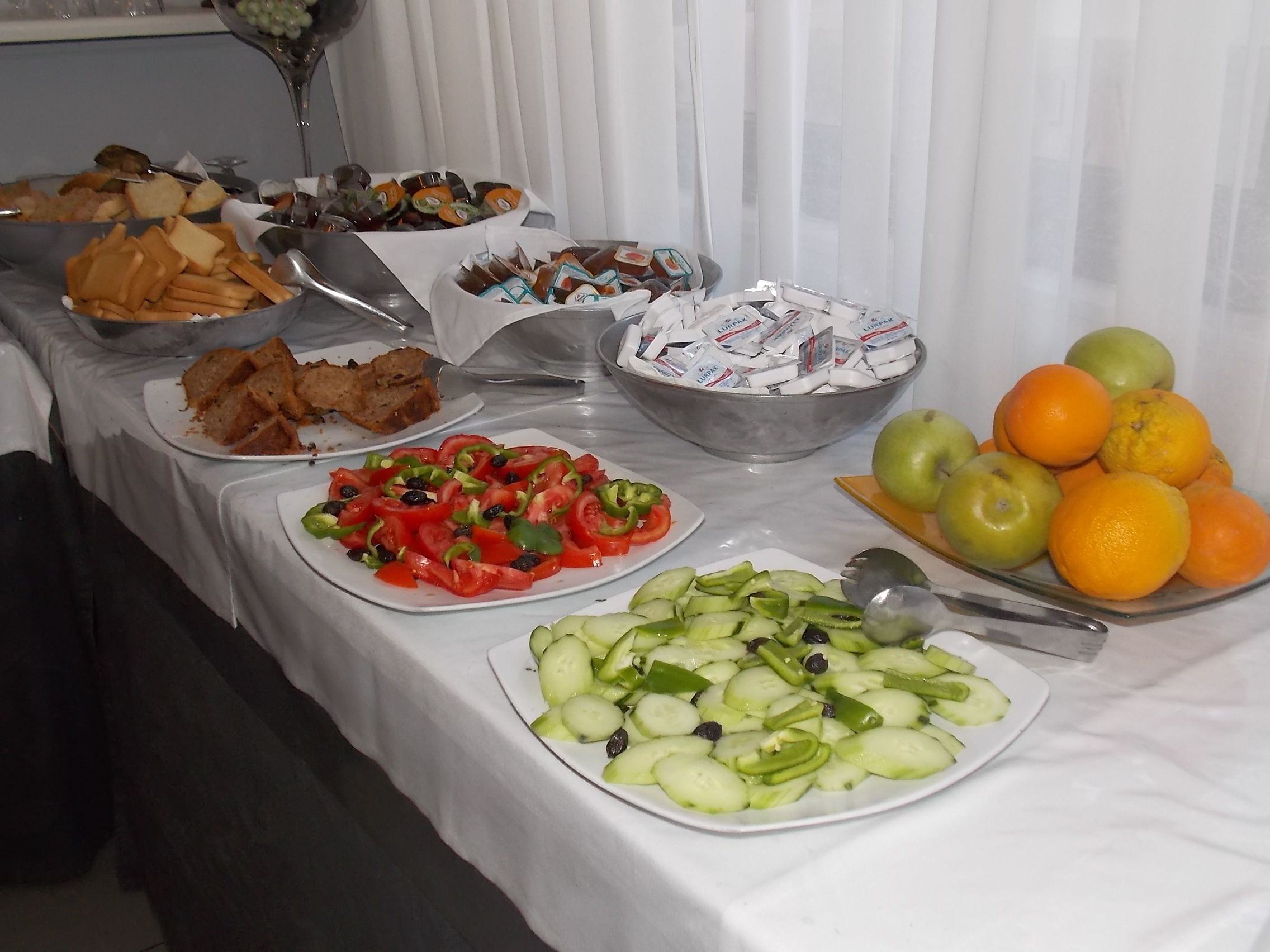 A buffet table with various food items including sandwiches, salads, fruits, and snacks.