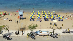 A beach with rows of blue and yellow umbrellas, a sandy shore, and a clear blue sea. - Hotel Danaos (Chania)
