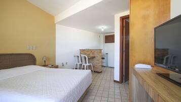 A hotel room with a bed, a TV, a desk, and a small kitchenette.