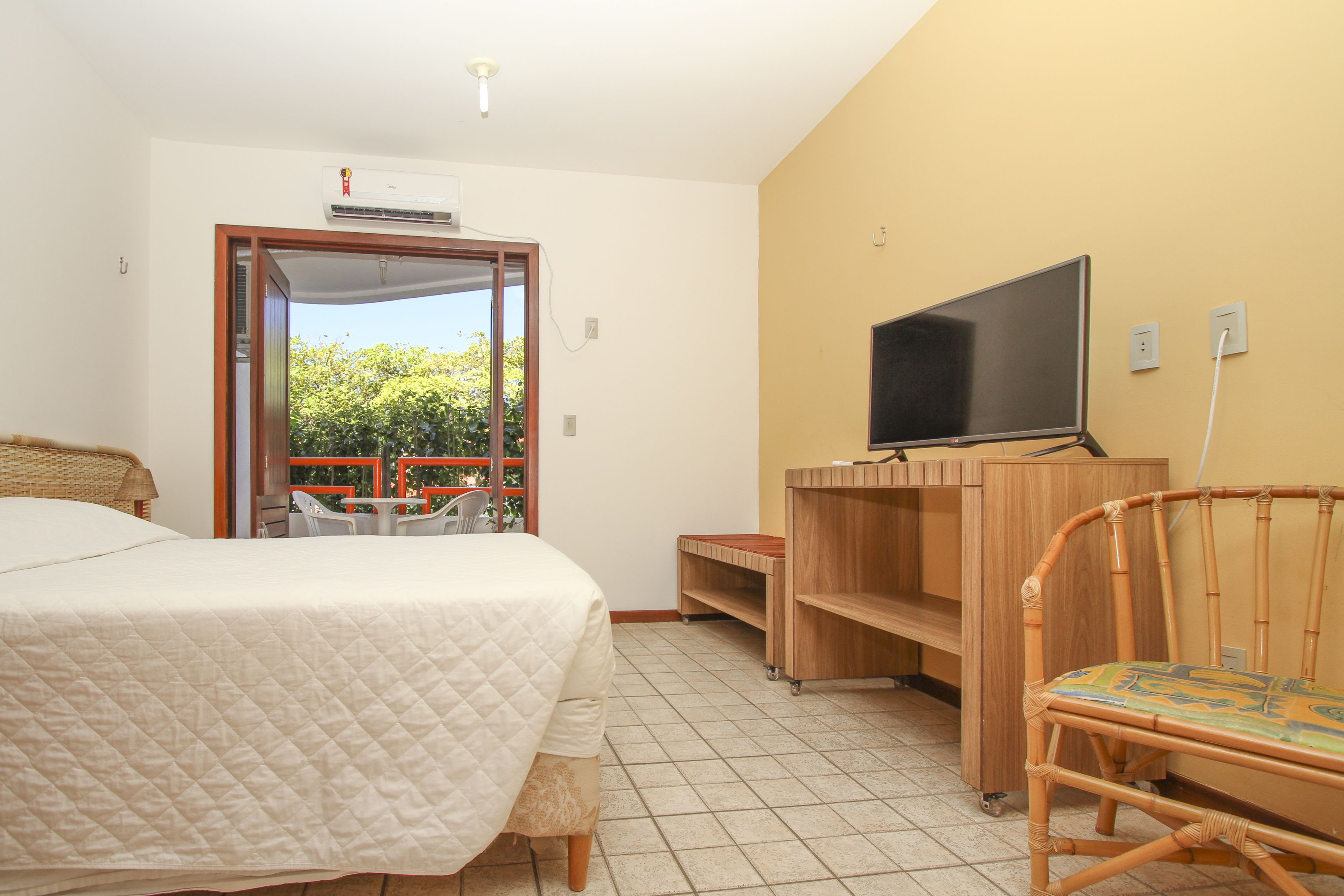 A bedroom with a bed, a TV, a chair, and a desk.