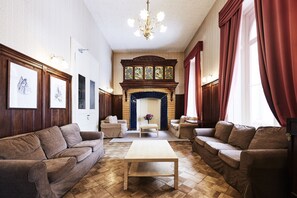 A spacious living room with a fireplace, two sofas, a coffee table, and a chandelier. - Maloja Palace (Bregaglia)