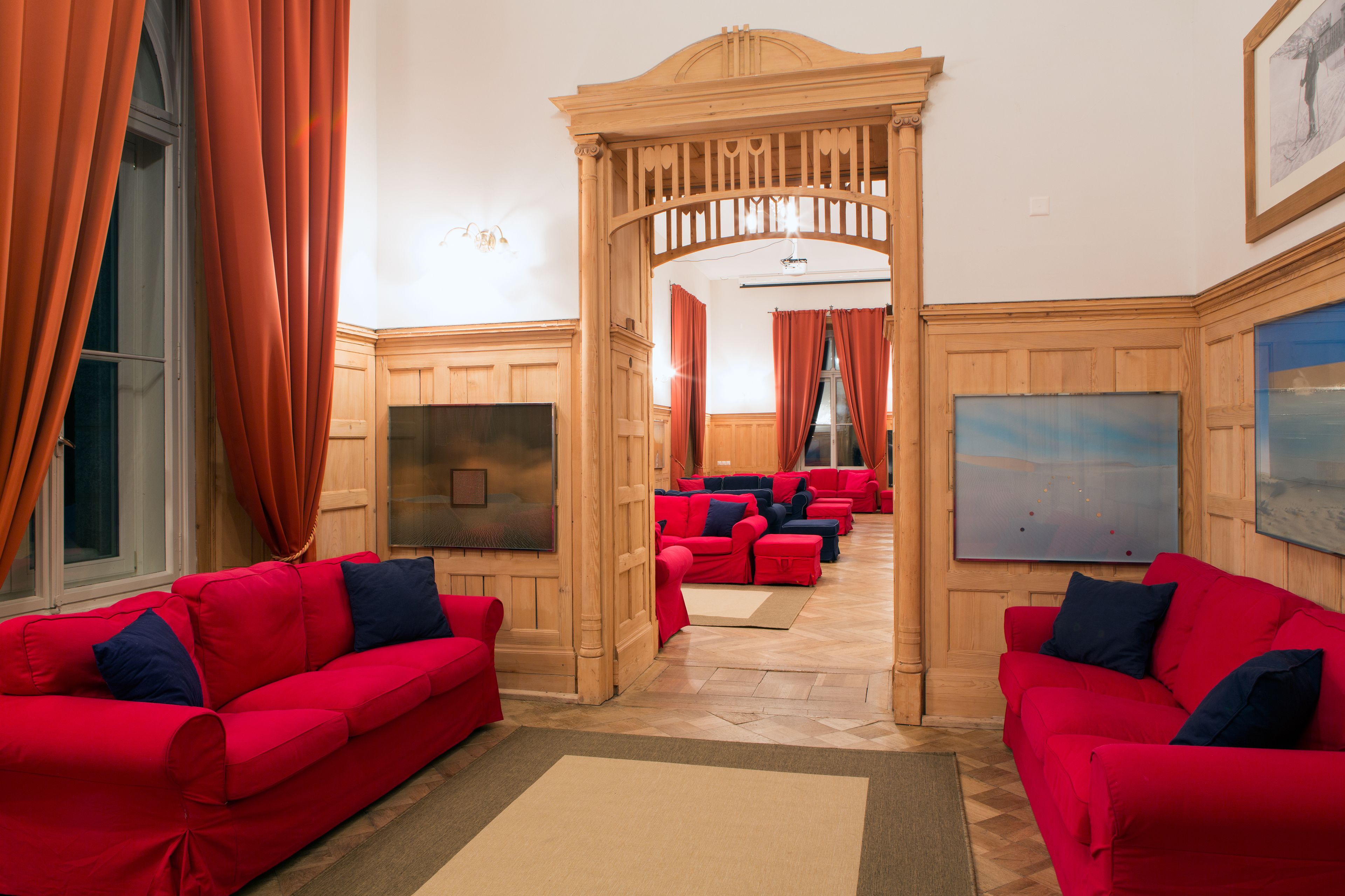 Un hall d’hôtel avec des canapés rouges, une décoration en bois et des œuvres d’art accrochées aux murs.