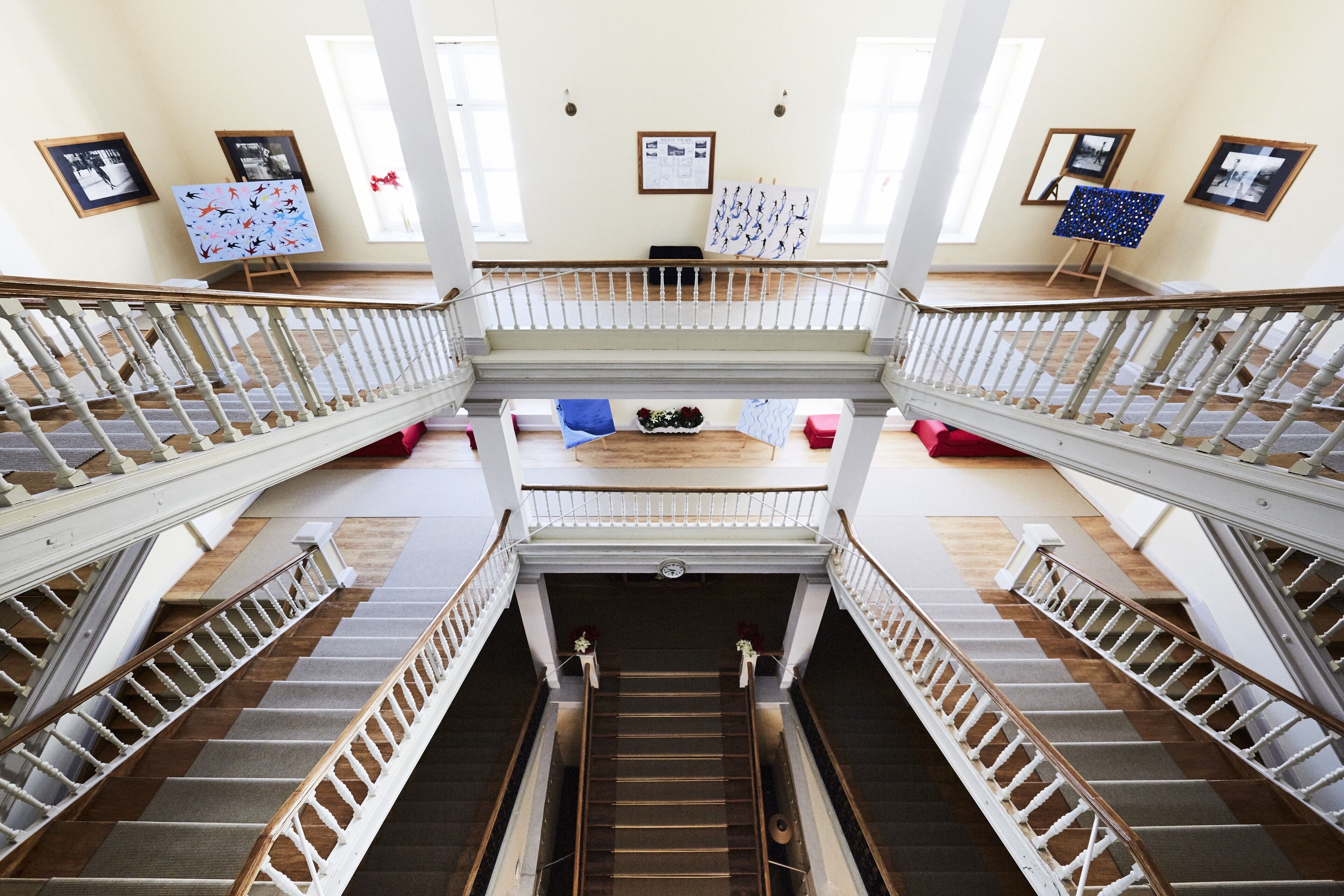 Un intérieur à plusieurs niveaux, doté d’un escalier central, de rampes et d’œuvres d’art exposées sur des chevalets.