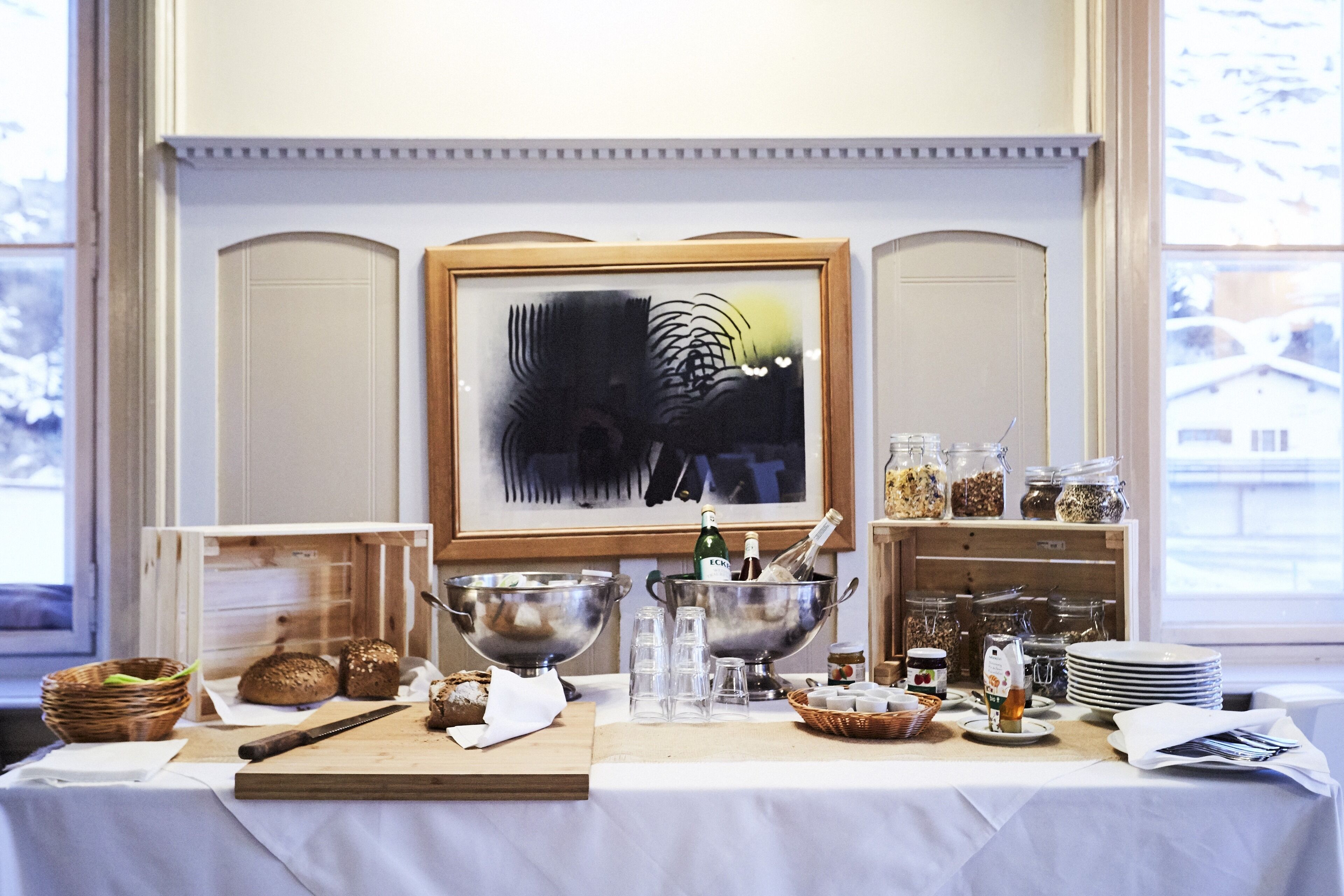 Un buffet de petit-déjeuner avec divers aliments, une bouteille d’eau et une œuvre d’art encadrée accrochée au mur.