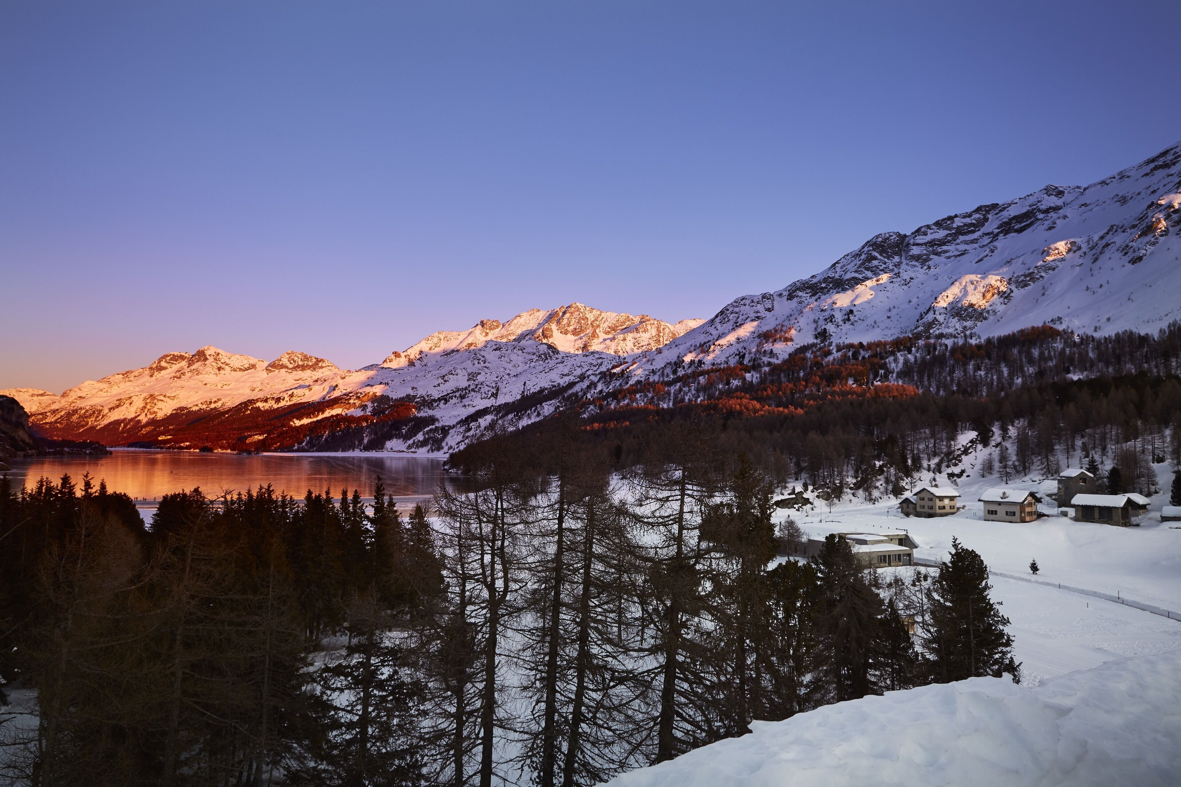 A mountainous landscape with a lake and snow-covered houses.