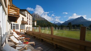 A wooden deck with lounge chairs and a view of a mountain landscape.
