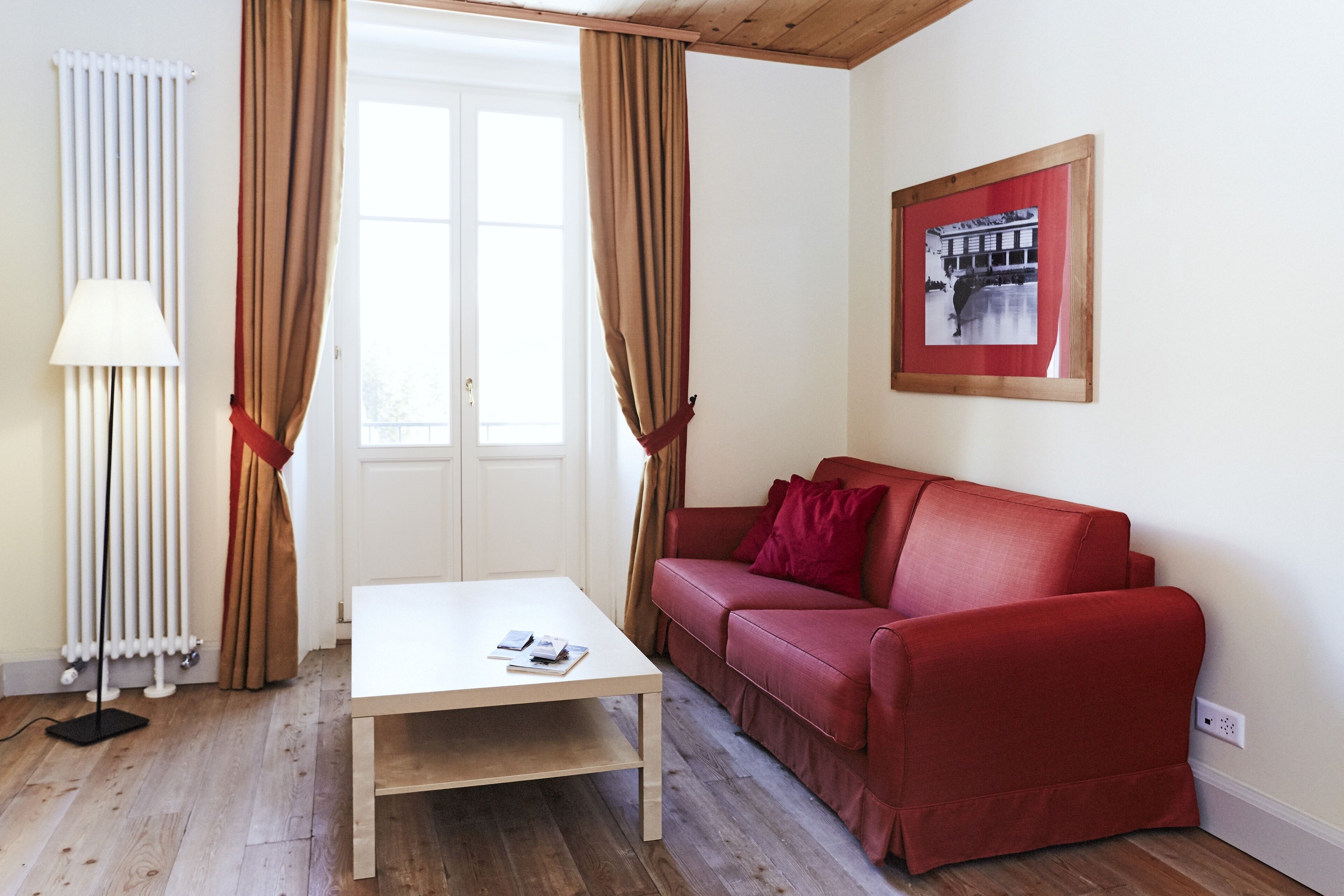 Een kamer met een witte tafel, een rode bank en een lijst met een afbeelding aan de muur.