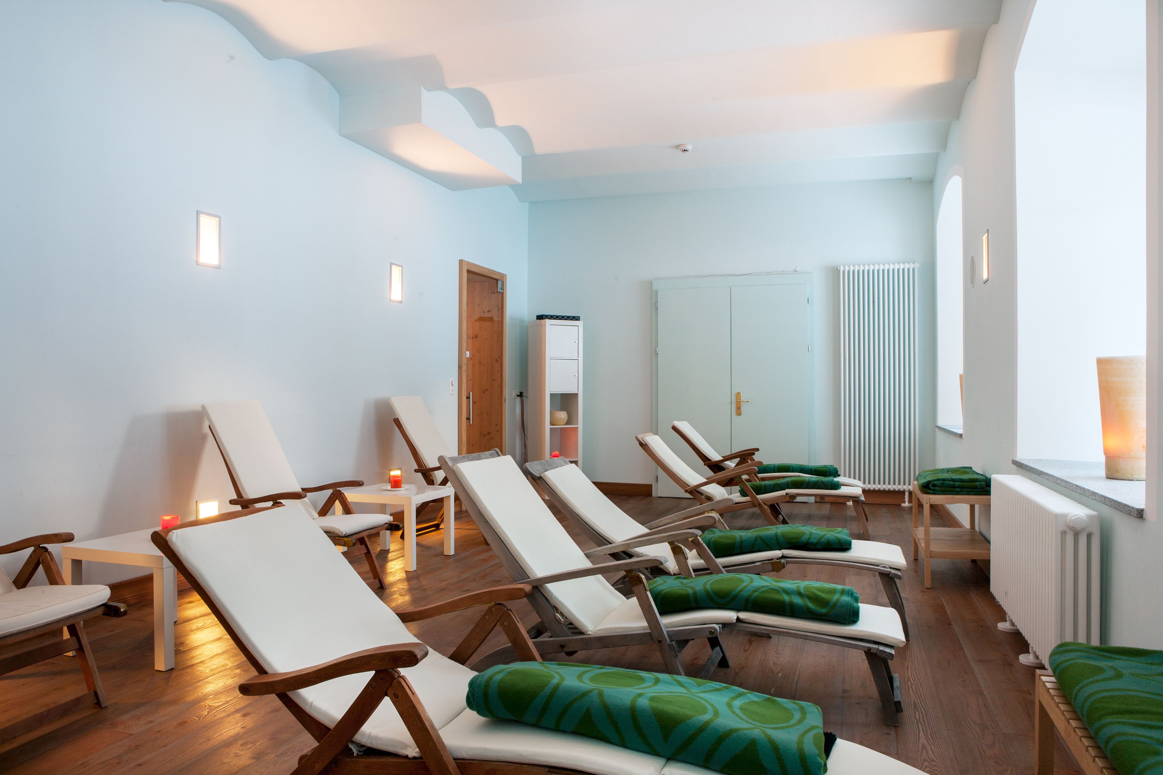 A room with multiple sun loungers, a small table, and a cabinet.