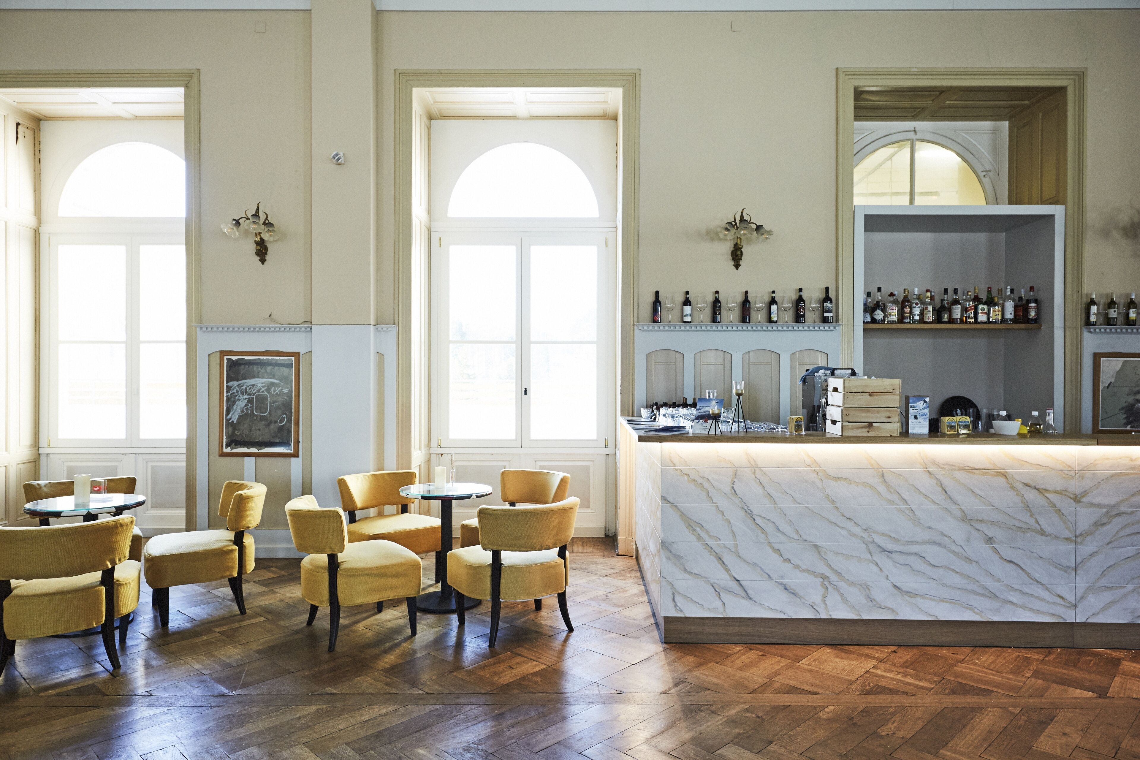 A hotel lobby with a marble reception desk, multiple seating areas, and a wine display.