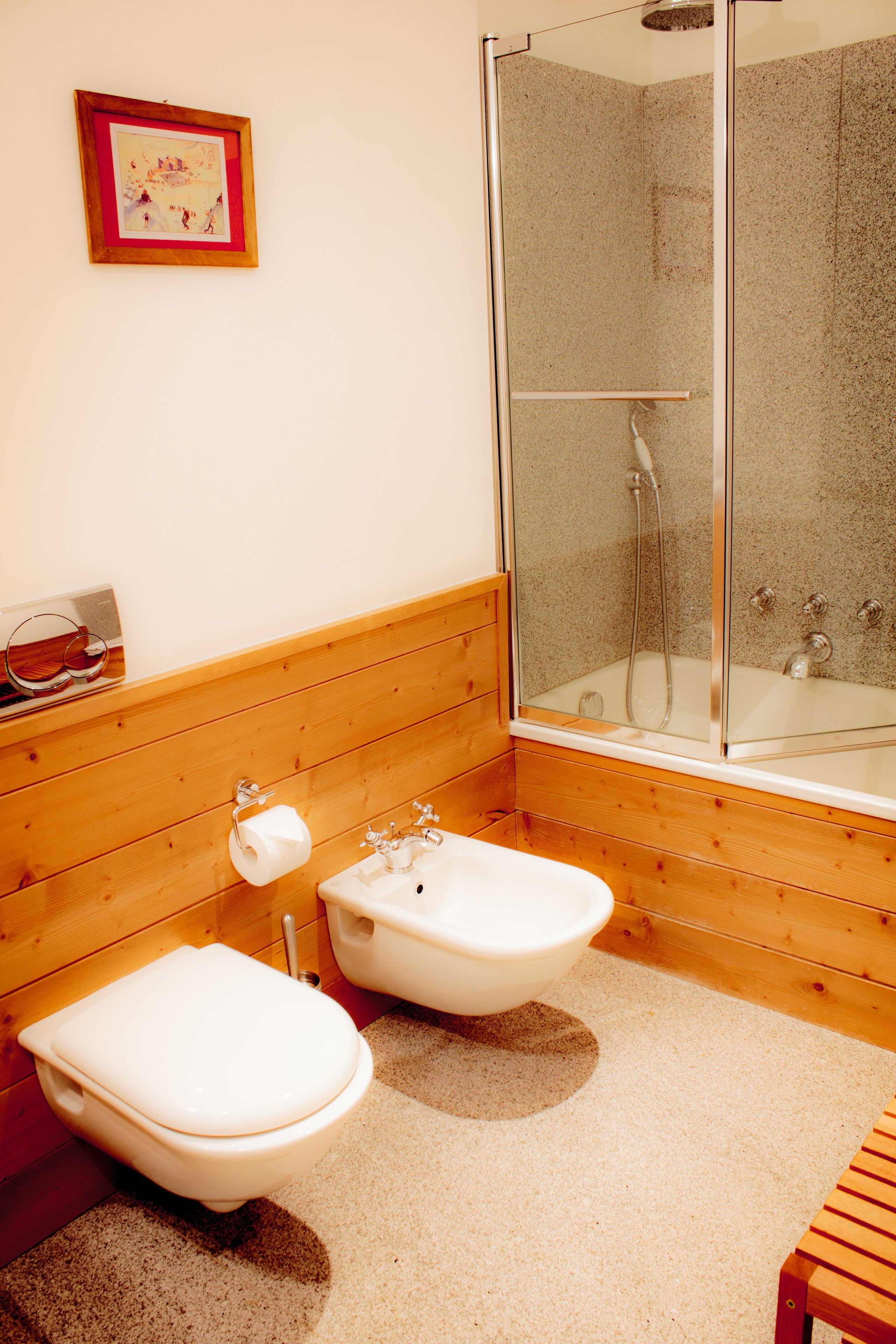 Ein Badezimmer mit Holzvertäfelung, einer Duschkabine, zwei Waschbecken und einer Toilette.