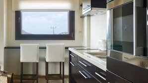 A modern kitchen with dark cabinetry, stainless steel appliances, and a window overlooking a landscape. - Sandima 37 Suites Hotel (Bodrum)