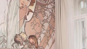 A bedroom with a large mural, a bed with brown bedding, a modern pendant light, and a window with curtains. - Hotel Klára (Prague)
