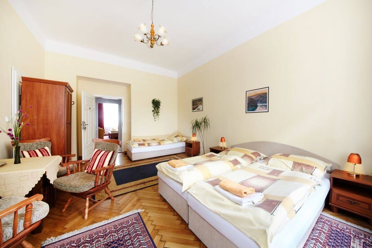 Un dormitorio con una cama grande, una silla de madera, una mesita y un candelabro.