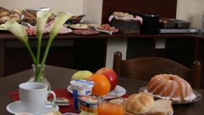 A breakfast table with plates of food, a vase with flowers, and a clock on the wall. - Hotel Klára (Prague)