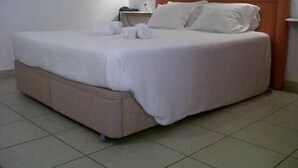 A neatly made bed with a headboard, a bedside table with a lamp, and a wall socket. - Torre Velha (Albufeira)
