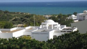 Ein Küstenort mit weißen Gebäuden, freiem Blick auf das Meer und üppigem Grün.