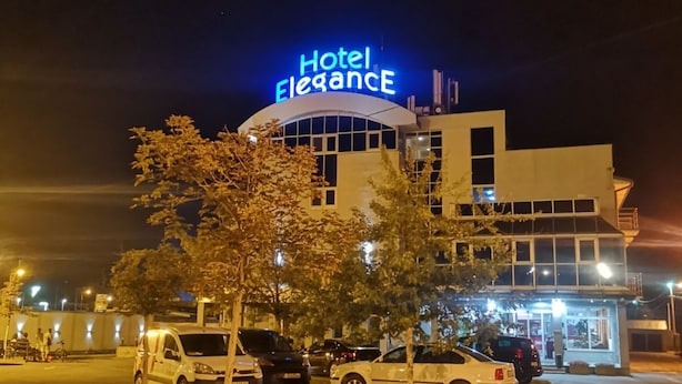 A hotel named 'Hotel Elegance' with a modern design, featuring a prominent illuminated sign, a parking lot with several cars, and a well-lit entrance. - Elegance Hotel (Belgrade)