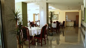 A spacious dining area with multiple tables and chairs, potted plants, and a clean, polished floor. - Elegance Hotel (Belgrade)