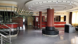 A hotel lobby with a reception desk, a staircase, and a large plant. - Elegance Hotel (Belgrade)