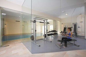 A modern gym with glass walls, weightlifting equipment, and a bench. - St Nicolas Elegant Residence (Paphos)