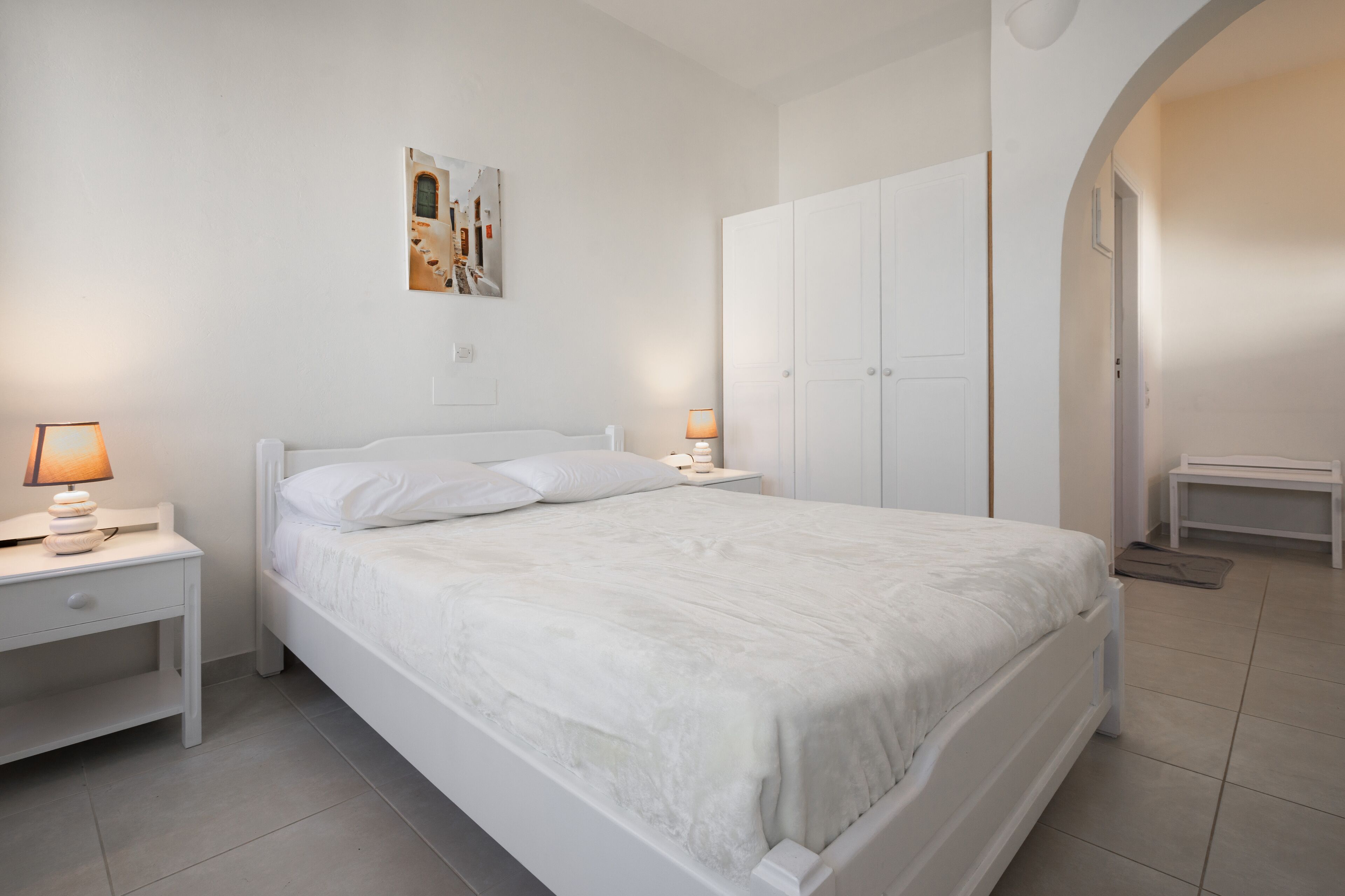 A neatly arranged bedroom with a bed, bedside tables, and a wardrobe.