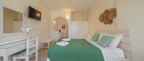 A bedroom with a bed, a desk, a chair, a TV, and a wall-mounted artwork.