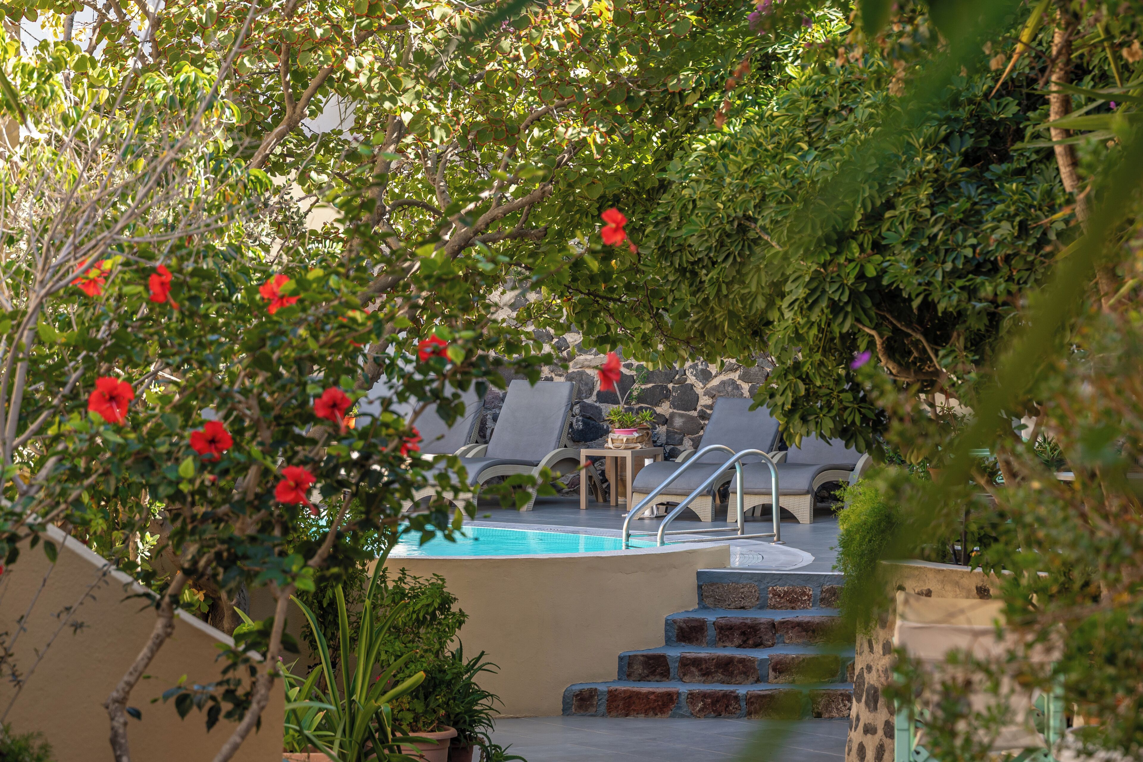 A pool area with steps leading to a lounge area with chairs and a table.