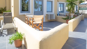 Un patio exterior moderno con mesa y sillas, plantas en macetas y una estructura de pérgola.