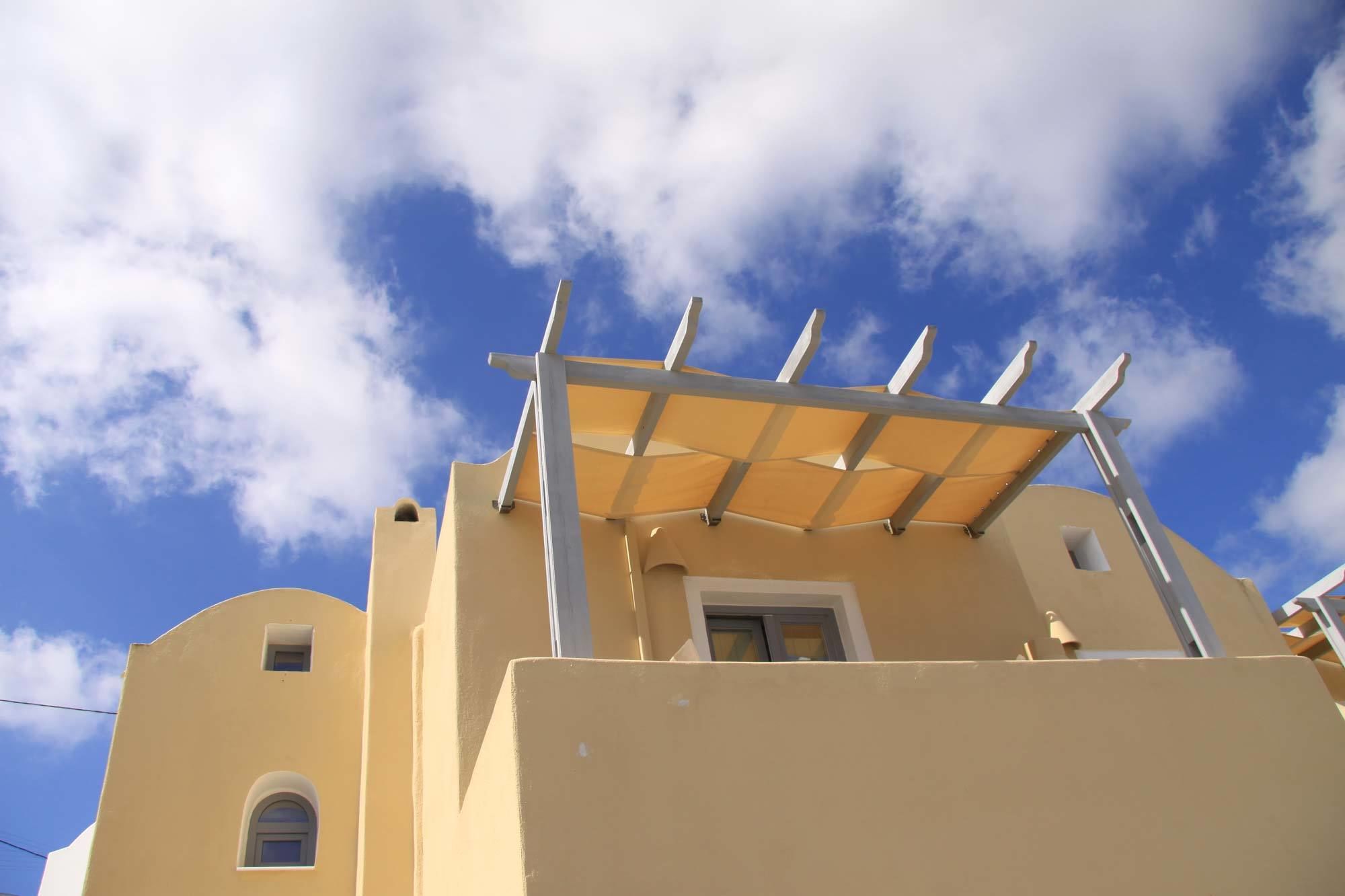 A building with a yellow facade and a pergola structure.