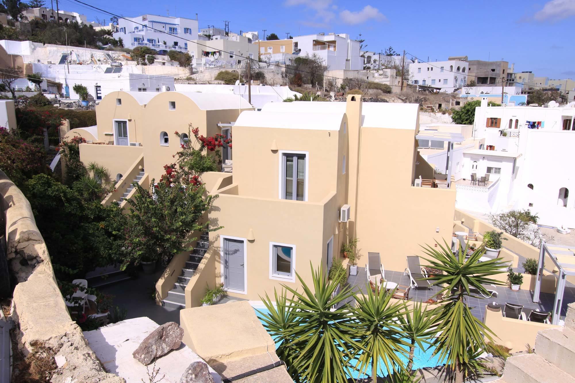 A Mediterranean-style building with a flat roof, a small balcony, and a pool area.