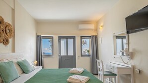 Una habitación de hotel con cama, dos ventanas, escritorio, silla y televisor.
