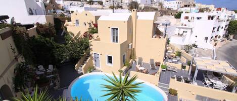 A residential building with a pool, surrounded by greenery and other buildings.