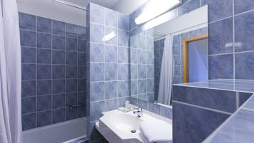 Een badkamer met douche, wastafel en spiegel.