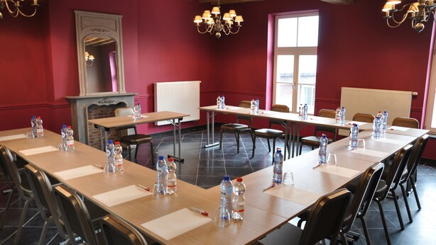 A conference room with a long table, chairs, water bottles, and a whiteboard. - Le Manoir du Capitaine (Seneffe)