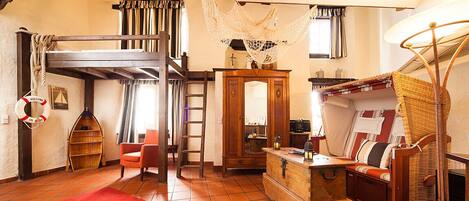 Een rustieke kamer met een hoogslaper, houten meubels, een hangmat en een reddingsboei aan de muur.