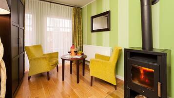 Een gezellige woonkamer met een houtkachel, twee gele fauteuils, een houten salontafel en een lamp met een gedraaid ontwerp.
